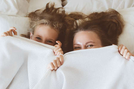 Mother and daughter hiding under blanket.の写真素材