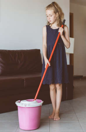 Little girl is cleaning the apartment. Mop the floor.の写真素材