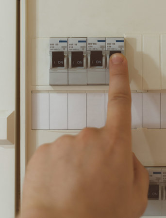 Male hand switching on fuse board.