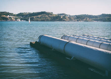 Large metal pipes heading to the river.の写真素材