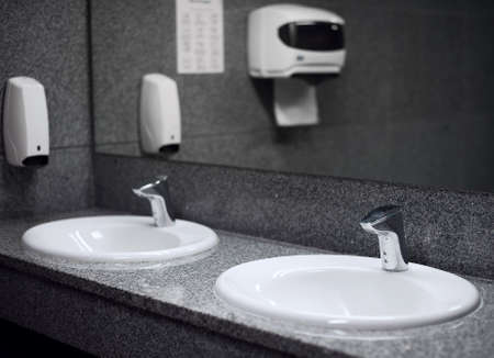Empty public toilet room with sinks and taps.の写真素材