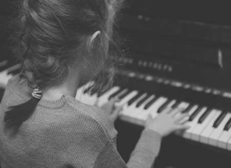Little girl learning to play the piano. Black and white.の写真素材