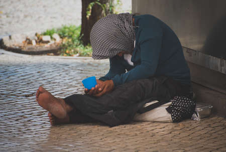 Homeless woman begs alms in the street.の写真素材