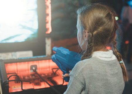 Little girl playing shooter game in theme park.