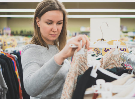 Woman choosing sweater in clothing store.