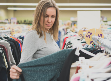 Woman choosing sweater in clothing store.