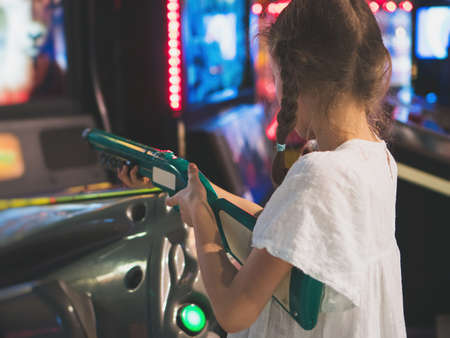 Little girl playing shooter game in theme park.の写真素材