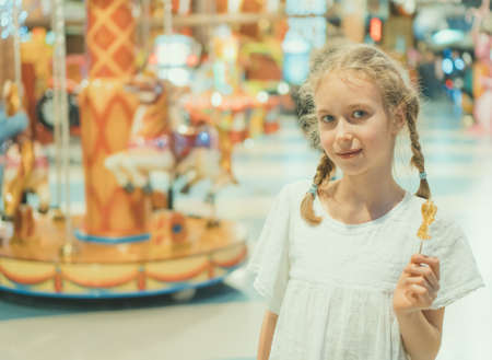 Cute little girl with lollipop in amusement park.の写真素材