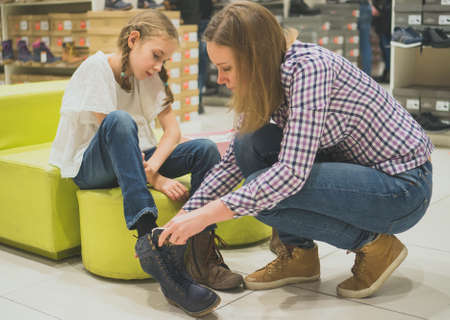 Mom chooses winter shoes for her daughter in the store.の写真素材