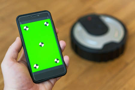 Man using mobile app to control robotic vacuum cleaner. Space for your text. Chroma key.の写真素材