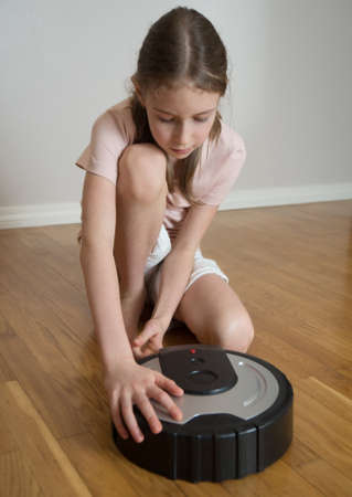 Little girl and robotic vacuum cleaner on the floor.の写真素材