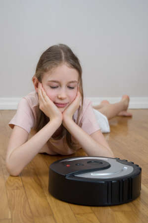 Little girl and robotic vacuum cleaner on the floor.の写真素材