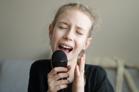 Cute little girl singing karaoke at home.の写真素材
