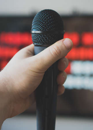 Man hand with karaoke microphone in front of TV.の写真素材