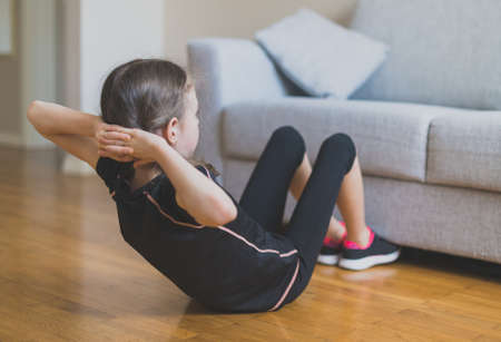 Little girl doing exercises for the abs at home.の写真素材