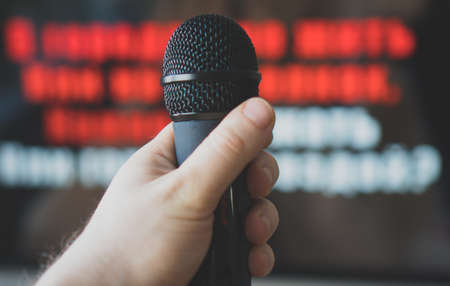 Man hand with karaoke microphone in front of TV.の写真素材