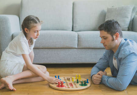 Little girl and her father playing ludo.の写真素材