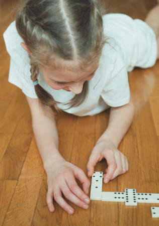 Cute little girl playing dominoes on the floor.の写真素材