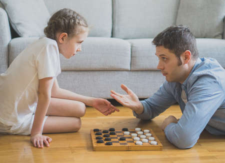 Father and daughter playing checkers board game.の写真素材