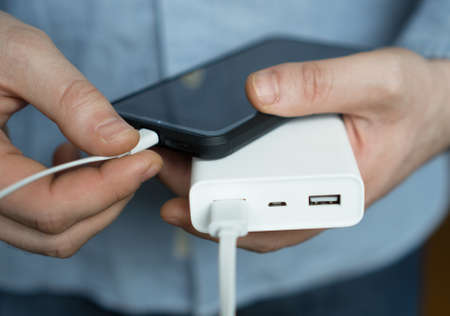 Man charging smartphone with power bank.の写真素材