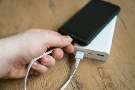 Man charging smartphone with power bank.の写真素材