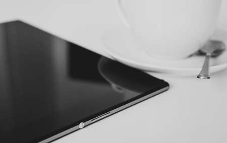 Black tablet pc with cup of coffee on the table.の写真素材