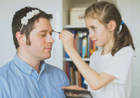 Cute little girl making makeup to her dad.の写真素材