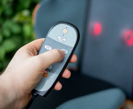 Man pressing button on remote control of electric massage seat.の写真素材