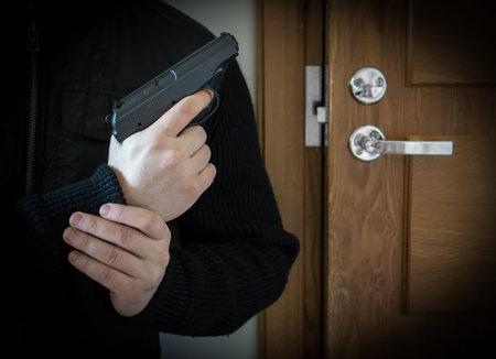 Armed man with gun waiting his victim near the door.