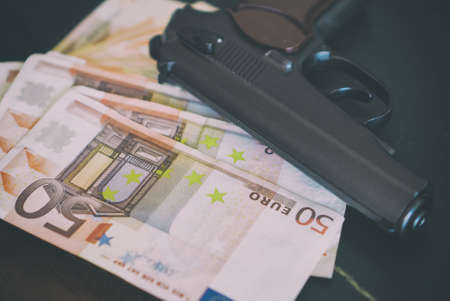 Lot of euro banknotes and gun on the table.の写真素材