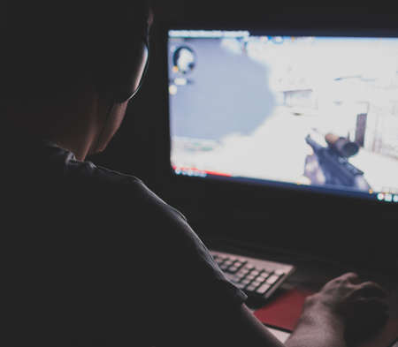 Man in headphones playing computer shooter game at night.の写真素材
