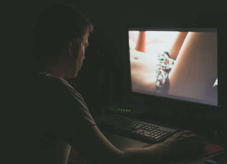Man watching erotic movie on computer at night.の写真素材