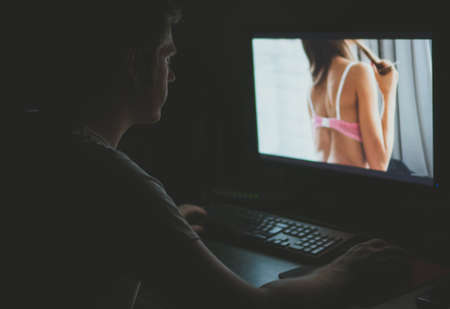 Man watching erotic movie on computer at night.の写真素材