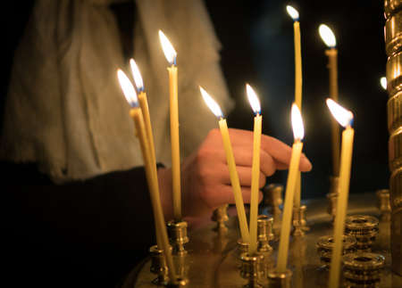 Woman lights the candle in russian orthodox church. Close-up.の写真素材