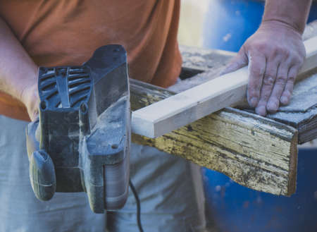 Handyman using electric sander machine outdoors.の写真素材