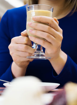 Woman in blue dress holding hot cup of coffee.