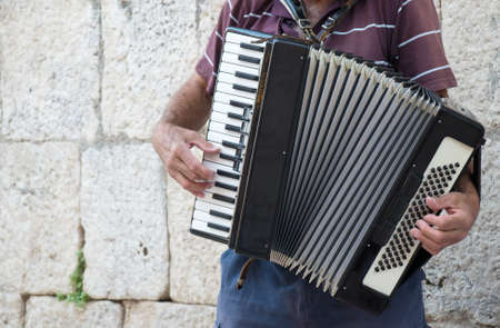 Elderly retired grandfather playing on accordion on the street.の写真素材
