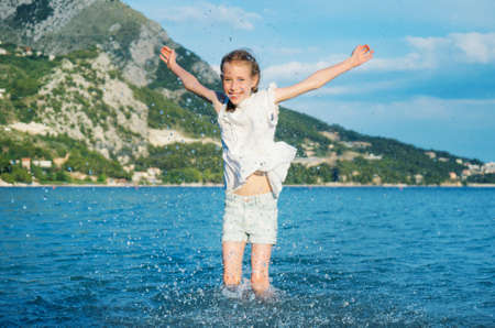 Little girl in clothes having fun in the sea.の写真素材