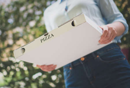 Pizza delivery woman holding pizza box.の写真素材
