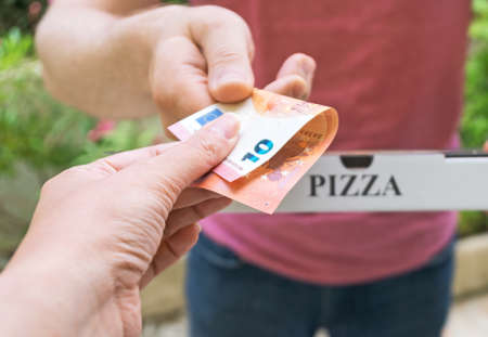 Man delivering pizza in box and taking payment.の写真素材