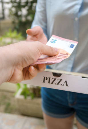 Woman delivering pizza in box and taking payment.の写真素材