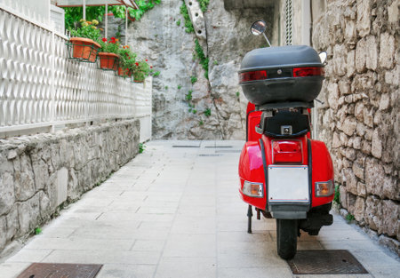 Red scooter parked on the empty street.のeditorial素材