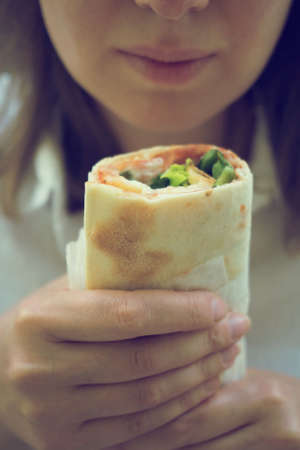 Woman holding sandwich wrap with ham, cheese and lettuce.の写真素材