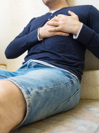 Man with a heart attack sitting on the ground.