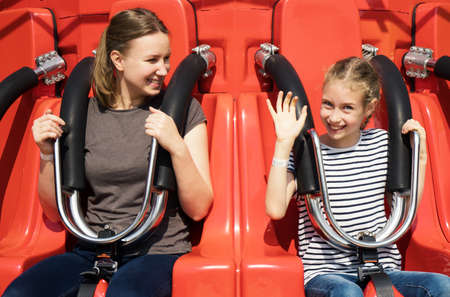 Mom and daughter are sitting on the attraction in the park.の写真素材