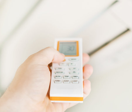 Hand holding remote control aimed at the air conditioner.