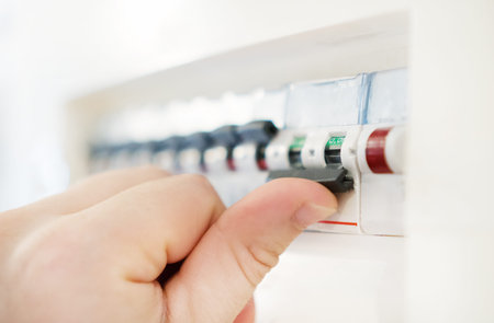 Male hand switching off fuse board.