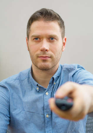 Handsome unshaved man watching TV at home.の写真素材