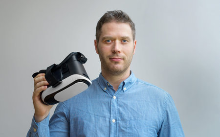 Handsome man holding virtual reality goggles. Space for your text.