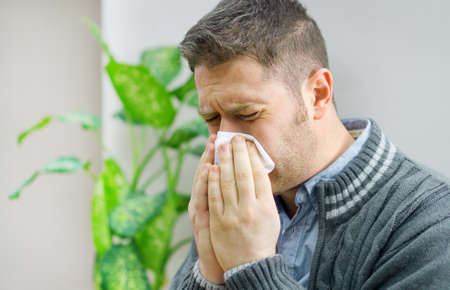 Handsome unshaved man blowing nose to napkin.の写真素材